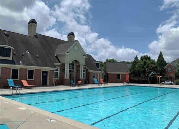 Relax by the pool surrounded by lounge chairs and a shaded area.