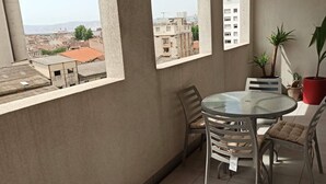 A balcony with a round glass table, two chairs, and potted plants.