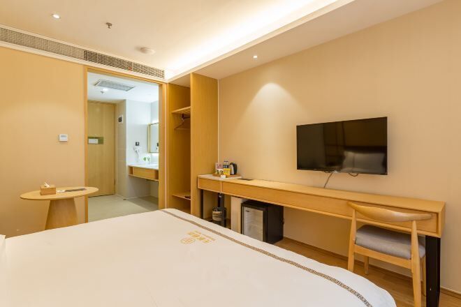 Ett hotellrum med en säng, ett skrivbord, en tv och ett litet bord.