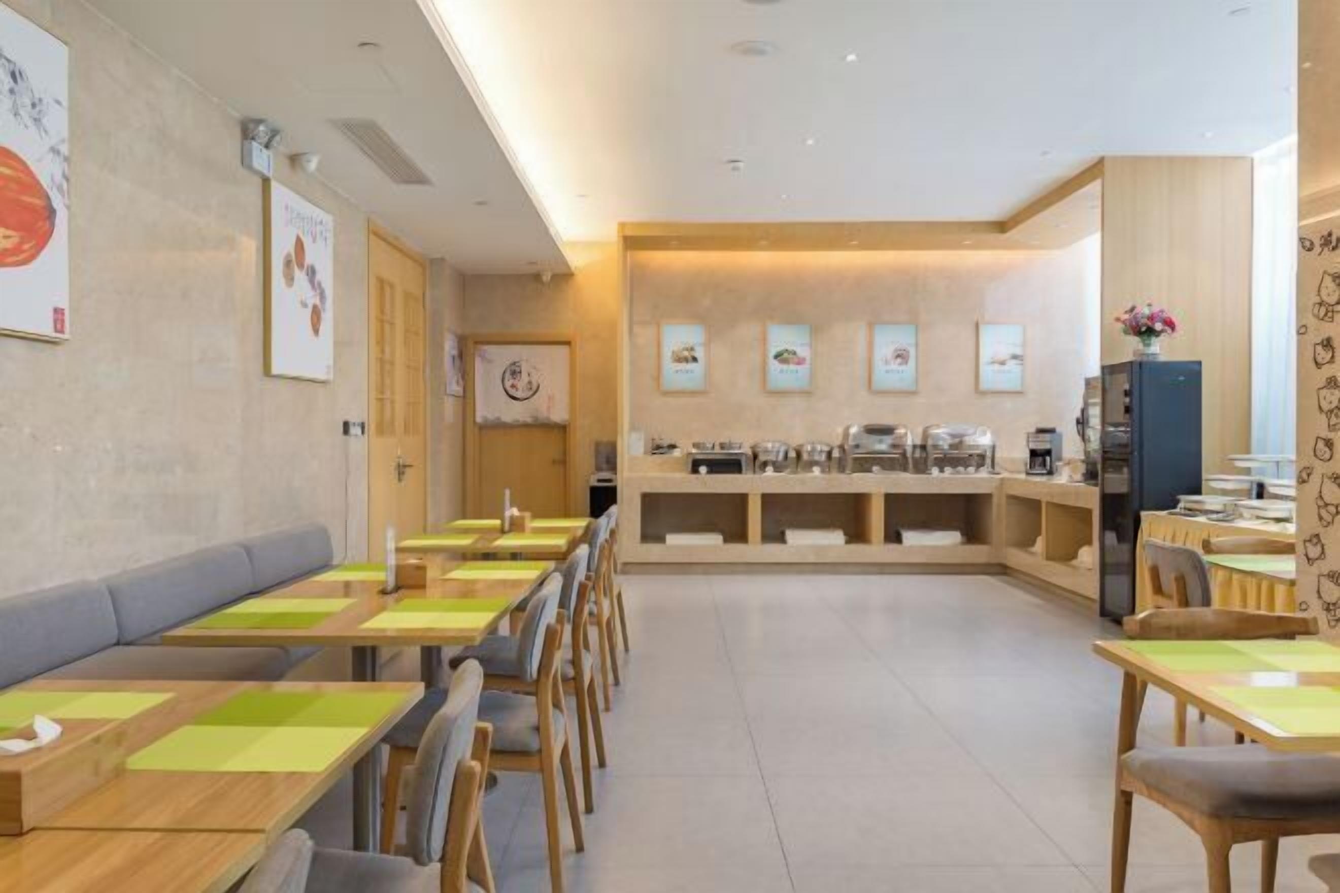 A restaurant with wooden tables and chairs, a counter with food items, and framed pictures on the walls.
