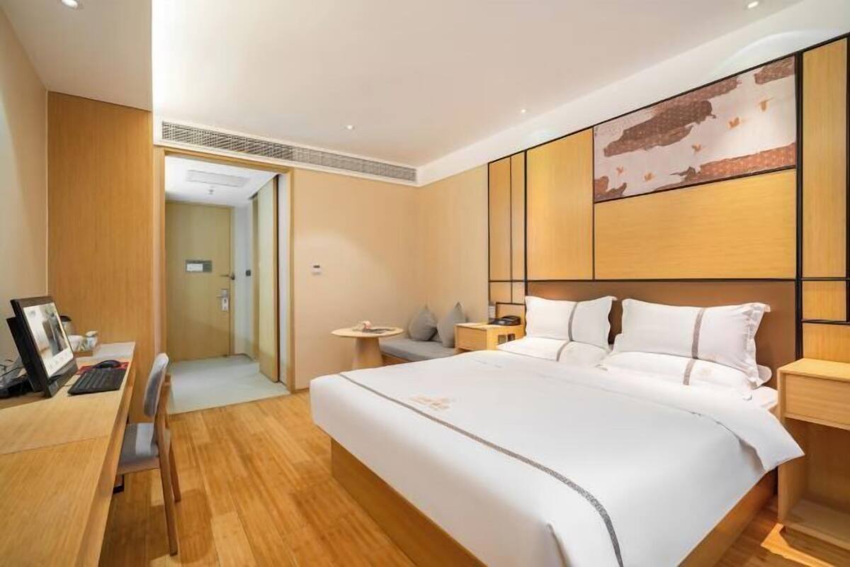 Una habitación de hotel con una cama grande, un escritorio con computadora y un pequeño rincón de descanso.