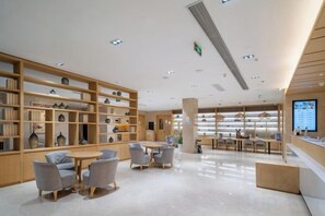 L’intérieur d’une bibliothèque moderne, avec des étagères, des espaces de lecture et un écran d’affichage numérique.