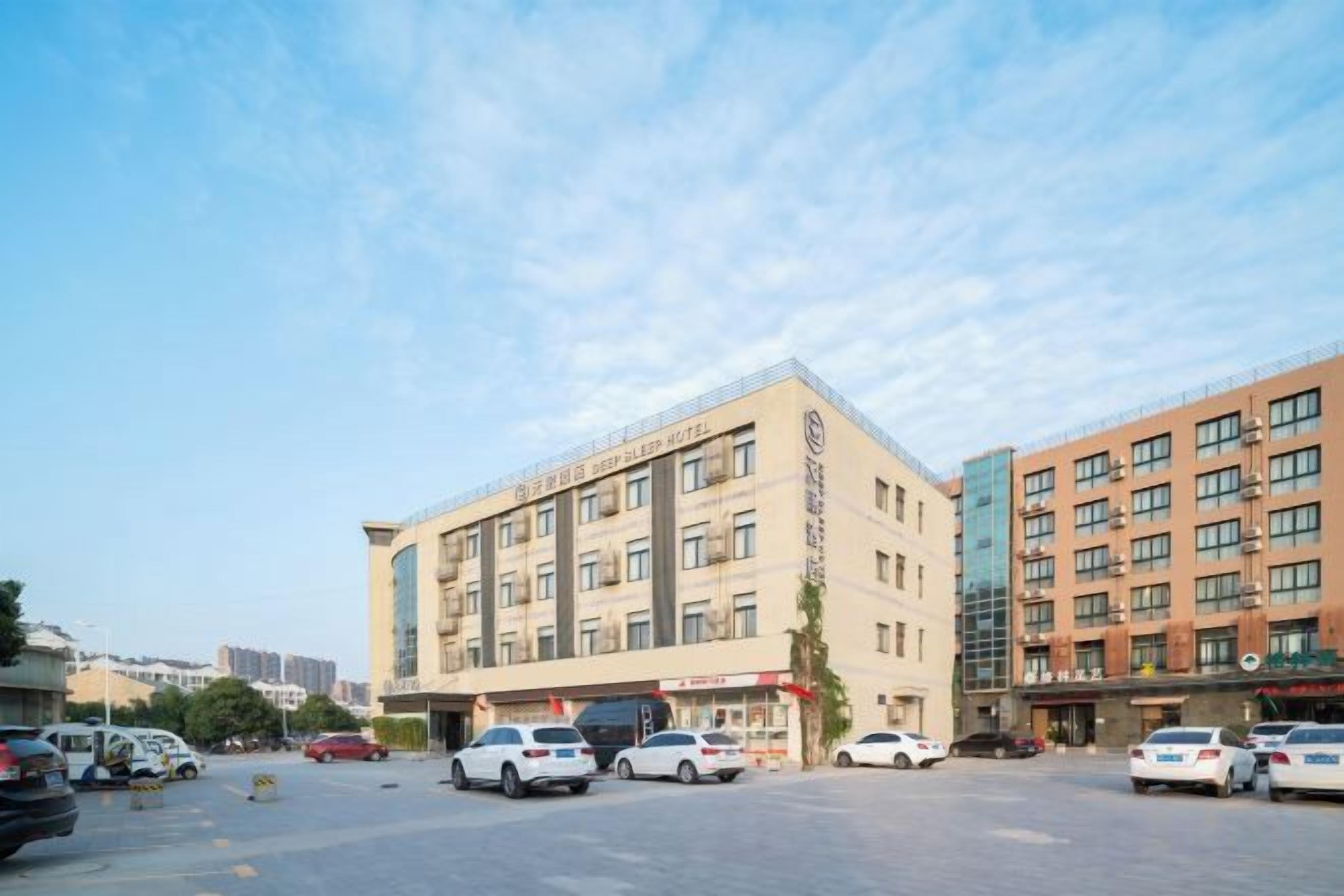 A hotel with a parking lot, multiple floors, and a clear sky.