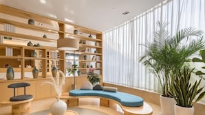 A modern living room with a curved sofa, wooden shelves, and potted plants. - Deep Sleep Hotel (Xuzhou High-Speed Railway Station Front Square Zhenxing Avenue) (Xuzhou)