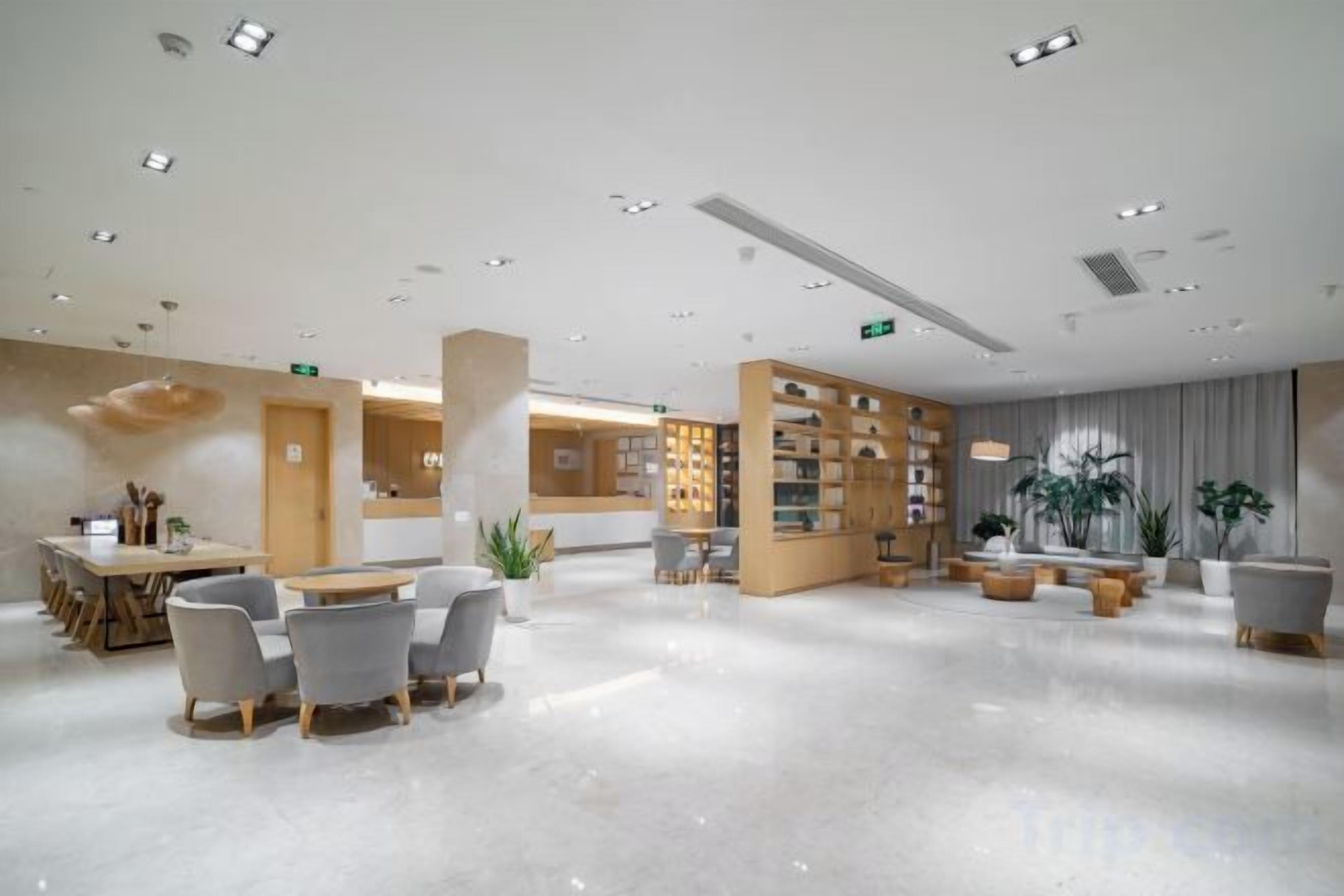 Eine großzügige Lobby mit Empfangsschalter, Sitzbereich und Bücherregal.