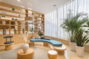 Une bibliothèque moderne dotée d’étagères, d’un espace de détente aux lignes courbes et de plantes en pot.
