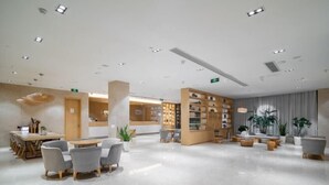 A modern hotel lobby with a reception desk, seating area, and a bookshelf. - Deep Sleep Hotel (Xuzhou High-Speed Railway Station Front Square Zhenxing Avenue) (Xuzhou)