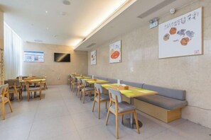 A restaurant with multiple tables and chairs, a long bench, and wall decorations. - Deep Sleep Hotel (Xuzhou High-Speed Railway Station Front Square Zhenxing Avenue) (Xuzhou)