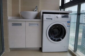 Un espace réduit dédié à la buanderie, comprenant un lave-linge et un évier.