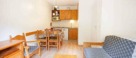 A compact living space with a dining area, kitchenette, and a sofa.
