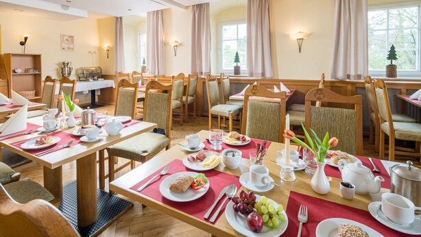 A breakfast setting with tables set for dining, including plates, cutlery, and beverages. - Landhaus Purschenstein (Neuhausen)