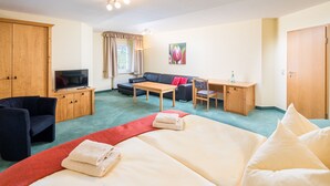 A hotel room with a bed, a desk, a sofa, a TV, and a wardrobe. - Landhaus Purschenstein (Neuhausen)