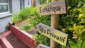 Ein hölzernes Wegweiser mit mehreren Schildern, die Dienstleistungen wie Massagen, Schönheitsbehandlungen, Wellness und einen zweitägigen Aufenthalt anzeigt.