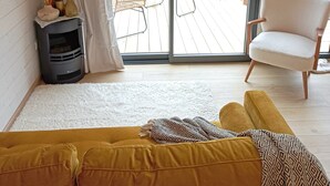 Ein gemütliches Wohnzimmer mit einer Couch, einem Flachbildfernseher, einem Kamin und einem Balkon mit Gartenmöbeln.