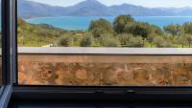Una habitación con un ventanal que ofrece vistas a un lago y montañas.