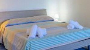 Habitación de hotel con una cama, una mesita de noche con lámpara y una obra de arte colgada en la pared.
