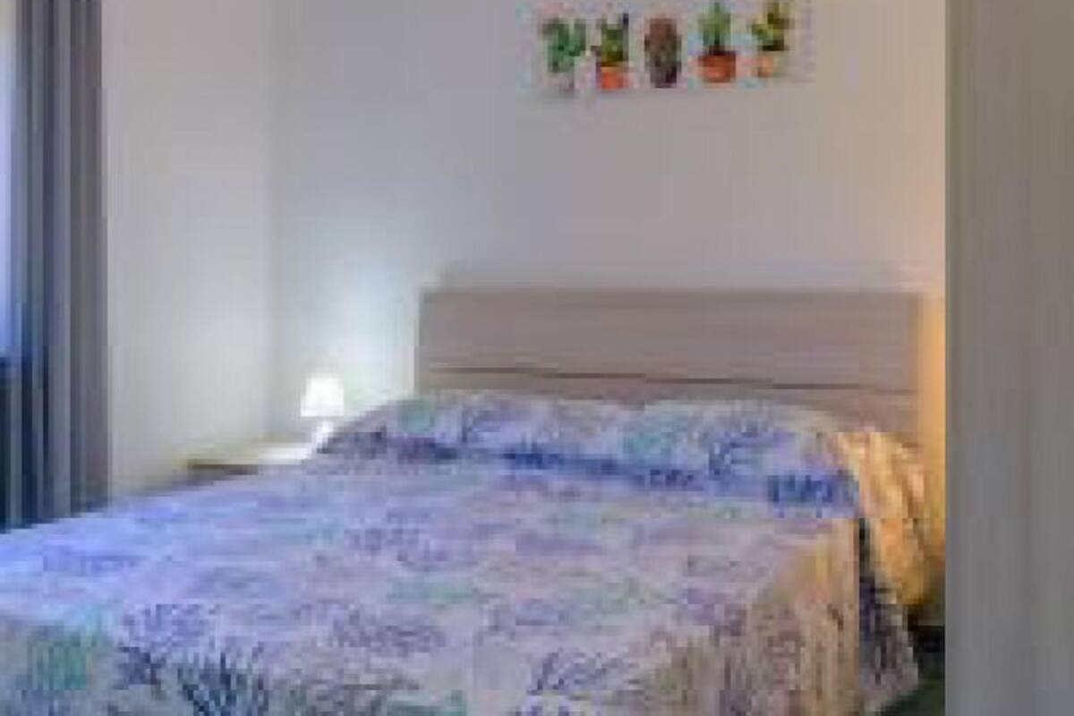 A bedroom with a bed, a nightstand, and a wall-mounted plant arrangement.