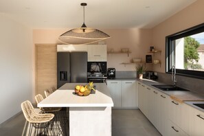 Una cocina moderna con una isla central, electrodomésticos integrados y un ventanal grande.