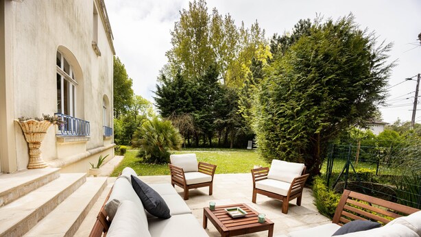 Une terrasse aménagée avec du mobilier d’extérieur, notamment un canapé, des fauteuils et une table.