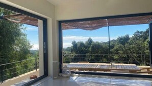 A modern room with large windows, a wooden table, and a view of a forested area. - "La Chamade" – 180° ocean view – 6 bedrooms – heated pool – near St. Tropez (LA CROIX VALMER)