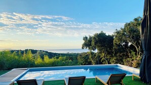 A swimming pool with three wooden lounge chairs and a wooden deck. - "La Chamade" – 180° ocean view – 6 bedrooms – heated pool – near St. Tropez (LA CROIX VALMER)