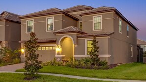 A two-story residential building with a symmetrical facade, a central arched entrance, and a well-maintained lawn.