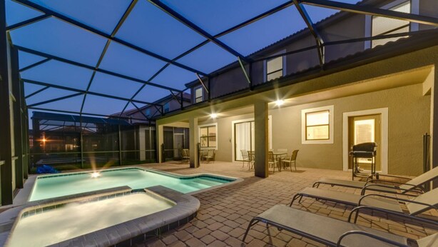 An outdoor swimming pool area with lounge chairs and a covered patio.
