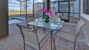 A glass-enclosed patio with a pool, outdoor seating, and a view of the landscape.