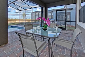 Un patio con paredes de vidrio, una piscina, mobiliario exterior y vistas del paisaje.