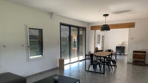 A modern living room with a sofa, a coffee table, and a dining area with a table and chairs. - Tobacco drying shed renovated into a loft, at CAPDROT in Périgord Pourpre (CAPDROT)