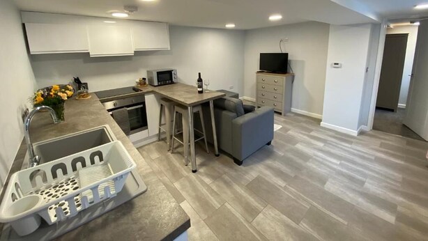 A modern kitchen with a dining area, built-in cabinets, a TV, and a small seating area.