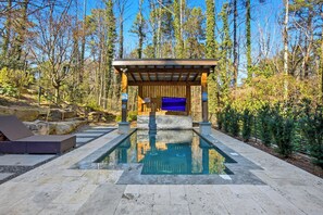 A pool area with a pergola, lounge chairs, and a stone pathway. - California Dreamers in the City (Atlanta)