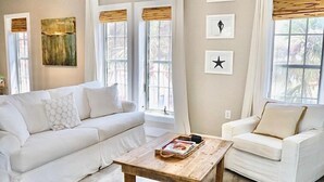 A modern living room with a white sofa, a wooden coffee table, and a hanging light fixture.