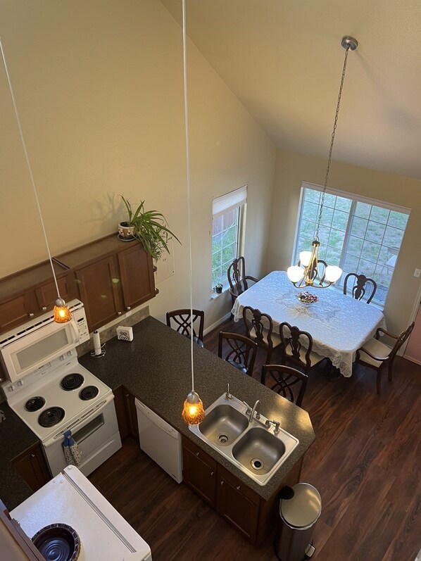 A compact kitchen with a dining area, featuring a central island, built-in appliances, and a view through large windows.