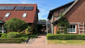 Um edifício com telhado de telhas vermelhas, painéis solares e fachada de tijolos.