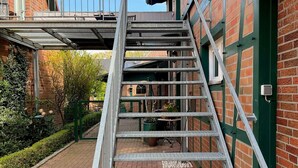 Escadaria de metal que leva a um edifício com porta verde.