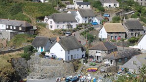 A coastal village with stone houses, a rocky beach, and kayaks. - Louvain (Helston)