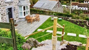 A stone house with a wooden deck and outdoor seating area. - Louvain (Helston)