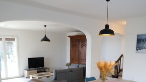 A modern living room with a wooden dining table, blue chairs, and a TV on a wooden stand. - Moulin à vent 3429 villa (Les Issambres)