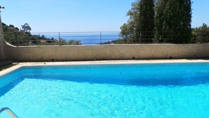 A rectangular swimming pool with clear blue water, surrounded by a concrete deck and a metal railing. - Moulin à vent 3429 villa (Les Issambres)