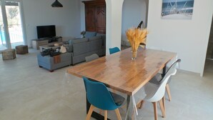 A spacious living area with a wooden dining table, blue chairs, a grey sofa, and a television. - Moulin à vent 3429 villa (Les Issambres)