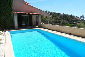 Ein rechteckiger Swimmingpool mit klarem, blauem Wasser, umgeben von einer Betonplattform und einem Metallgeländer.