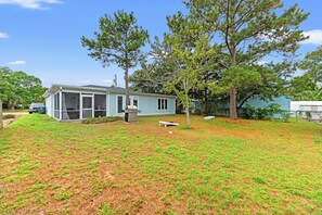 A residential property with a covered porch, a barbecue grill, and a well-maintained lawn. - A Little Peace of Paradise- 3 Bed/2 Bath House -Walk to Beach-Screened In Porch (North Myrtle Beach)