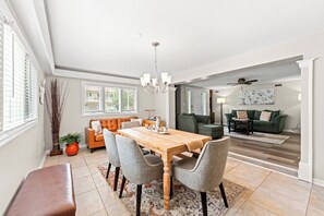 A spacious dining area with a wooden table and chairs, a chandelier, and a view of the living room through an open doorway. - A Little Peace of Paradise- 3 Bed/2 Bath House -Walk to Beach-Screened In Porch (North Myrtle Beach)