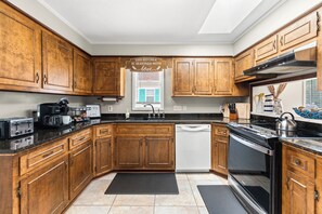 A kitchen with wooden cabinets, a dishwasher, a stove, and a coffee maker.