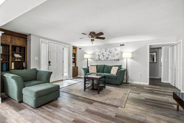 A living room with a sectional sofa, a coffee table, and a ceiling fan.