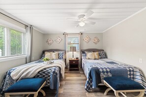 Ein Schlafzimmer mit zwei Betten, einem Deckenventilator und einem Nachttisch mit Lampe.