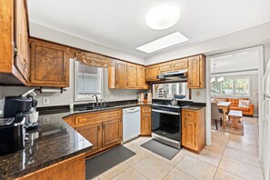 A modern kitchen with wooden cabinets, a built-in oven, and a dishwasher. - A Little Peace of Paradise- 3 Bed/2 Bath House -Walk to Beach-Screened In Porch (North Myrtle Beach)