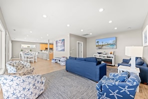 A modern living room with a blue sofa, a patterned armchair, and a fireplace. - 4202 Destination Sand Dollar - Oceanfront Pool (North Myrtle Beach)