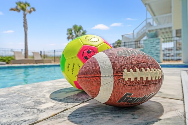 A poolside with a football and a soccer ball.